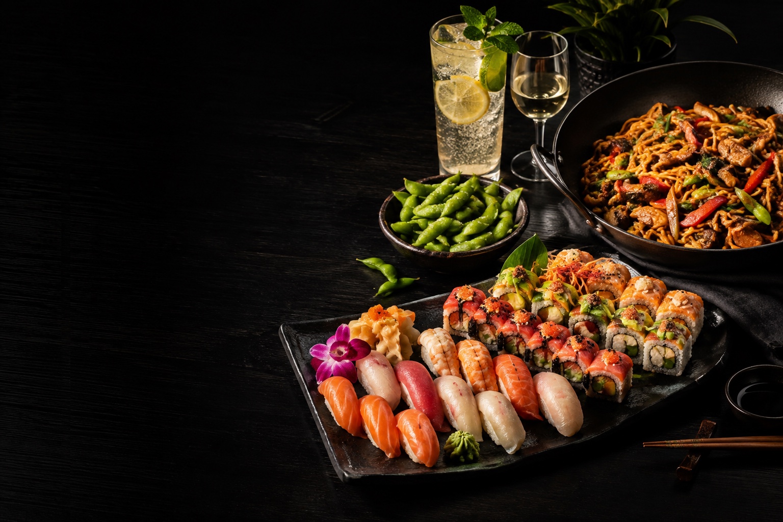 Sushi, Wok-Gerichte und Getränke auf einer gedeckten Tafel — illustratives Food-Motiv